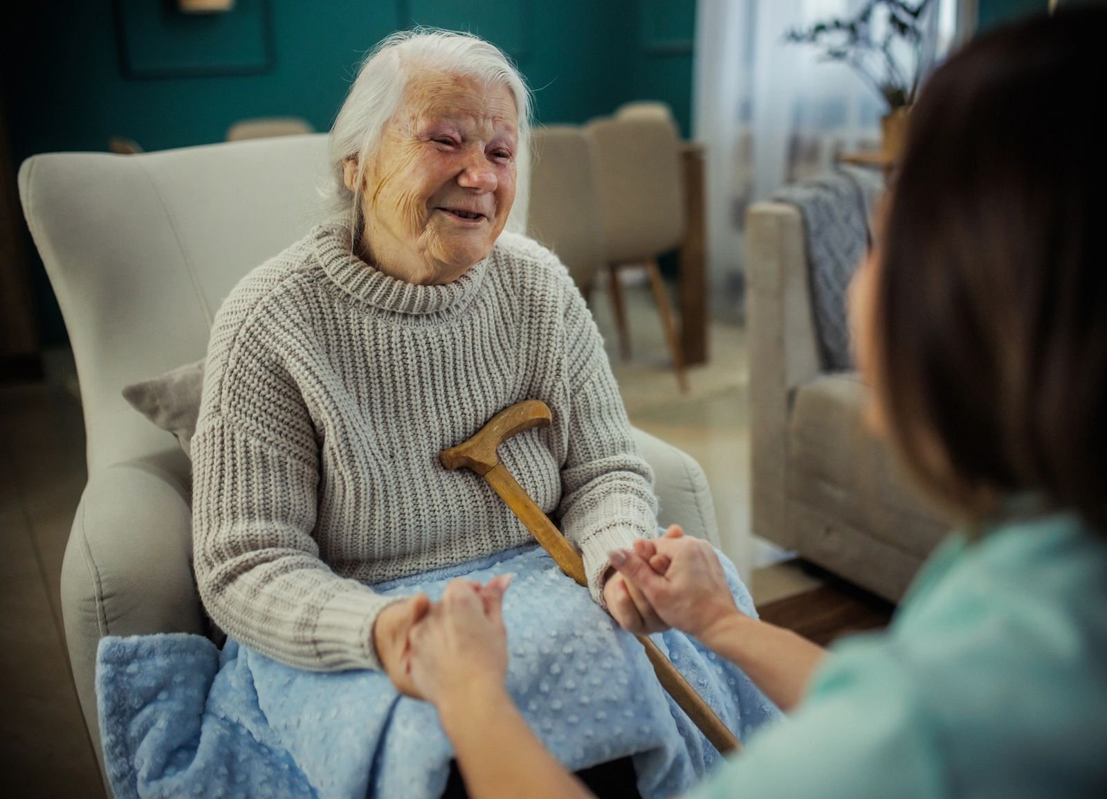 Caregiver gently holding an elderly patient's hands, showing care and support